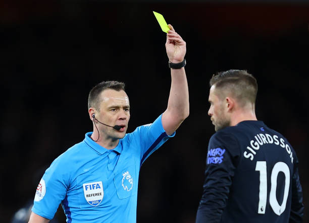 Match Referee Stuart Attwell shows a yellow card to Gylfi Sigurdsson of Everton during the Premier League match between Arsenal FC and Everton FC at Emirates Stadium on February 23, 2020 in London, United Kingdom.