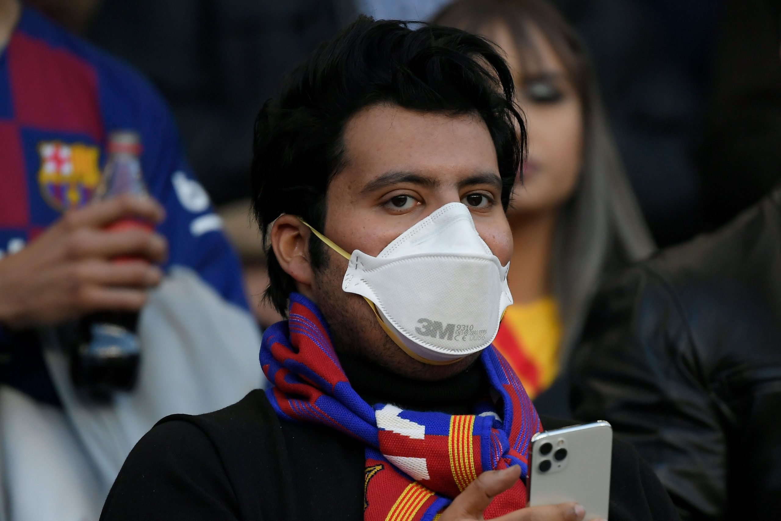 A man wearing a protective mask in light of the coronavirus outbreak waits for the start of the Spanish league football match between FC Barcelona and Real Sociedad at the Camp Nou stadium in Barcelona on March 7, 2020.