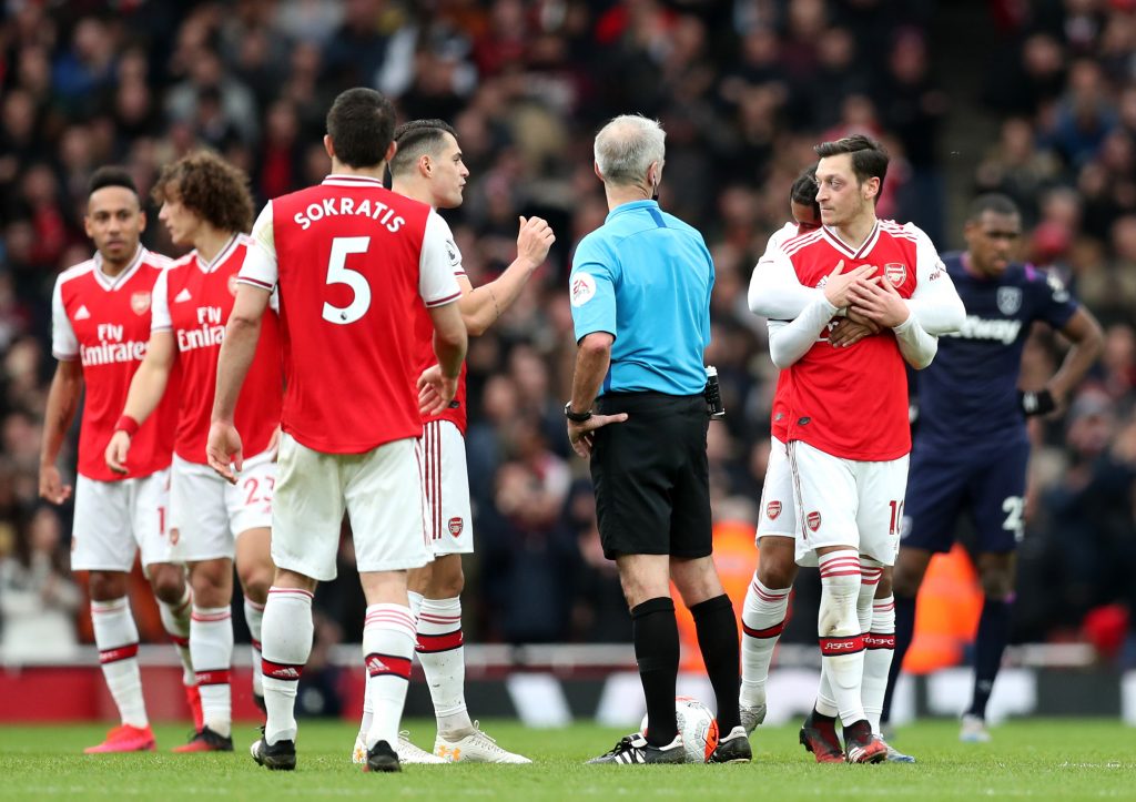 Granit Xhaka and Mesut Ozil of Arsenal speak to referee Martin Atkinson during the Premier League match between Arsenal FC and West Ham United at Emirates Stadium on March 07, 2020 in London, United Kingdom.