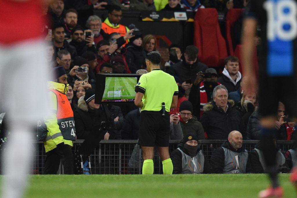 Referee Serdar Gozubuyuk reiews a handball decision on the VAR screen during the UEFA Europa League round of 32 second leg football match between Manchester United and Club Brugge at Old Trafford in Manchester, north west England, on February 27, 2020. 