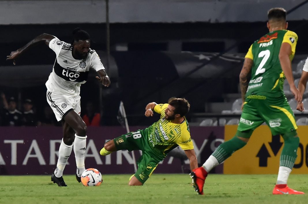Argentina's Defensa y Justicia player Francisco Cerro (C) vies for the ball with Paraguay's Olimpia player Emmanuel Adebayor during their Copa Libertadores football match at Manuel Ferreira stadium, in Asuncion, on March 11, 2020. (Photo by NORBERTO DUARTE / AFP via Getty Images)