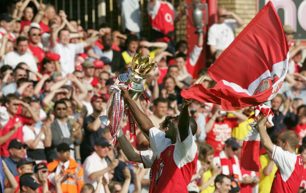 LONDON, UNITED KINGDOM: Arsenal's Sol Campbell (L) and an unidentified teammate hold the Premiership trophy after Arsenal won the Premiership title and defeating Leicsester City 15 May, 2004 at Highbury in London. Arsenal defeated Leicester City 2-1 and finish the season undefeated. AFP PHOTO/JIM WATSON 