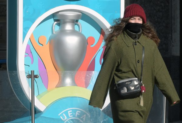A woman wearing her scarf wrapped around her face walks past the Euro 2020 countdown clock - displaying 449 days left before the event - in downtown Saint Petersburg on March 19, 2020. - The European Championship, due to be played in June and July this year, has been postponed until 2021 because of the coronavirus pandemic, European football's governing body UEFA said on March 17, 2020. UEFA announced that the new proposed dates for the tournament were June 11 to July 11 next year, as Euro 2020 becomes Euro 2021. (Photo by OLGA MALTSEVA / AFP) (Photo by OLGA MALTSEVA/AFP via Getty Images)