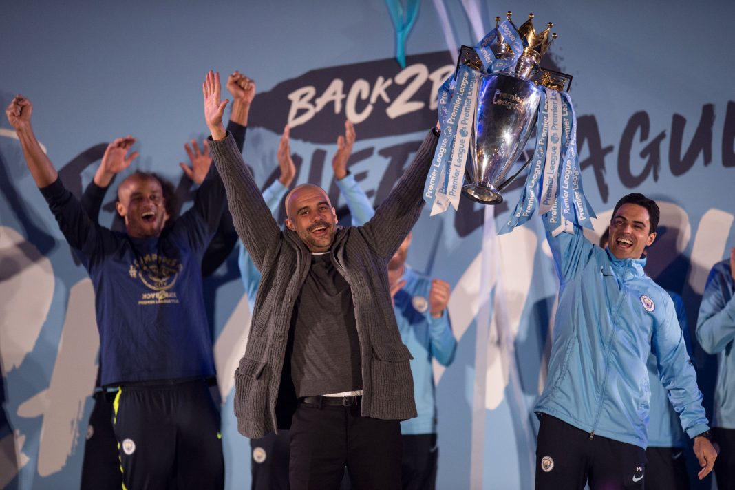 Manchester City's Spanish manager Pep Guardiola (C), Manchester City assistant coach Mikel Arteta (R) and Manchester City's Belgian defender Vincent Kompany (L) show the Premier League trophy to supporters outside the Etihad Stadium in Manchester, northern England on May 12, 2019. - Manchester City held off a titanic challenge from Liverpool to become the first side in a decade to retain the Premier League on Sunday by coming from behind to beat Brighton 4-1 on Sunday. (Photo by OLI SCARFF / AFP)