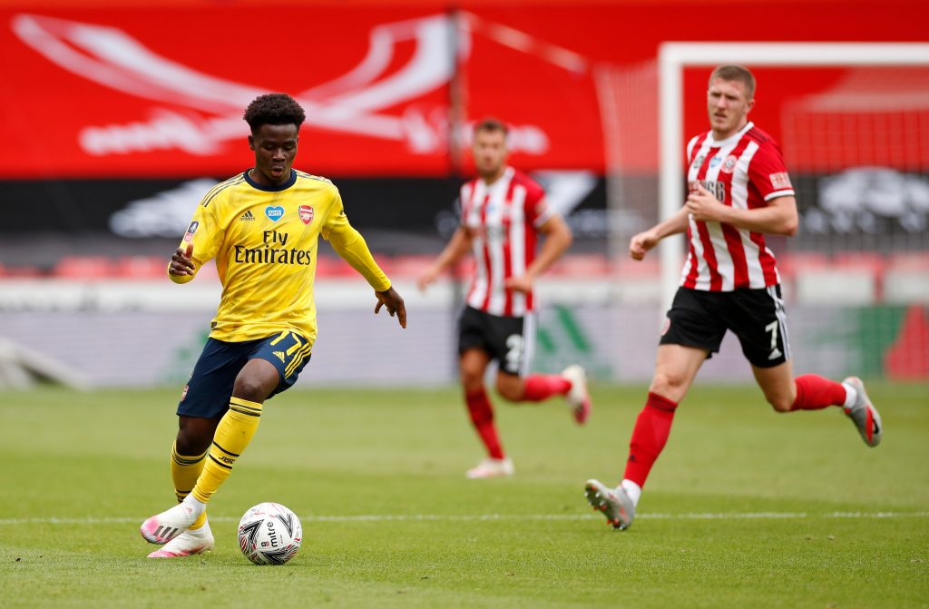 Arsenal's English striker Bukayo Saka (L) runs with the ball during the English FA Cup quarter-final football match between Sheffield United and Arsenal at Bramall Lane in Sheffield, northern England on June 28, 2020. (Photo by ANDREW BOYERS / POOL / AFP) / RESTRICTED TO EDITORIAL USE. No use with unauthorized audio, video, data, fixture lists, club/league logos or 'live' services. Online in-match use limited to 120 images. An additional 40 images may be used in extra time. No video emulation. Social media in-match use limited to 120 images. An additional 40 images may be used in extra time. No use in betting publications, games or single club/league/player publications. / (Photo by ANDREW BOYERS/POOL/AFP via Getty Images)