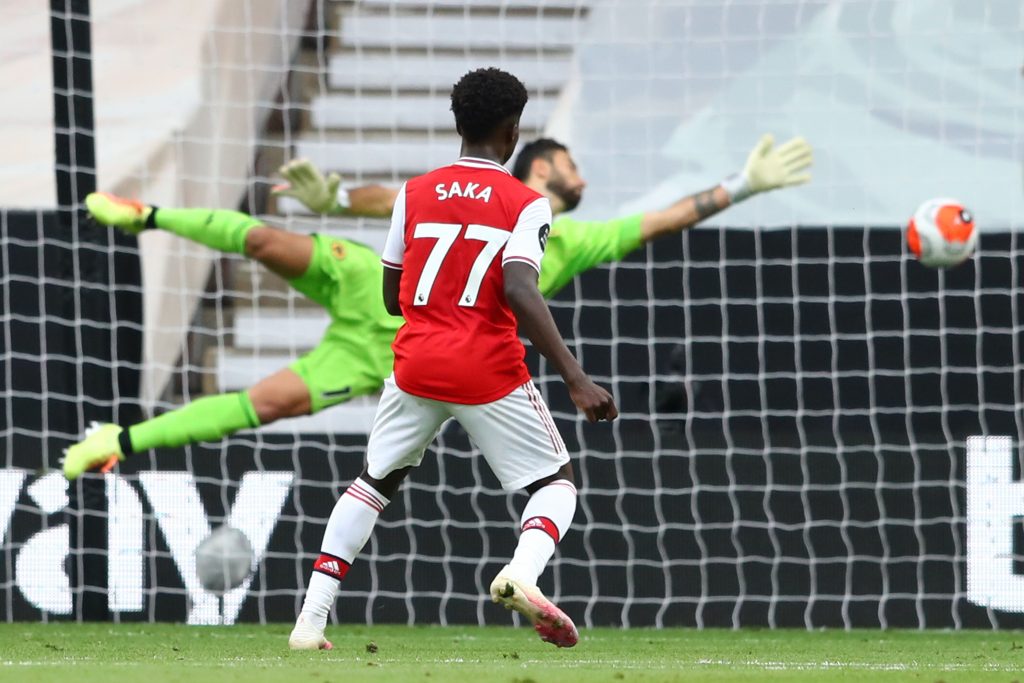 Arsenal's English striker Bukayo Saka watches his shot beat Wolverhampton Wanderers' Portuguese goalkeeper Rui Patricio to score the opening goal during the English Premier League football match between Wolverhampton Wanderers and Arsenal at the Molineux stadium in Wolverhampton, central England on July 4, 2020. (Photo by Michael Steele / POOL / AFP) / RESTRICTED TO EDITORIAL USE. No use with unauthorized audio, video, data, fixture lists, club/league logos or 'live' services. Online in-match use limited to 120 images. An additional 40 images may be used in extra time. No video emulation. Social media in-match use limited to 120 images. An additional 40 images may be used in extra time. No use in betting publications, games or single club/league/player publications. / (Photo by MICHAEL STEELE/POOL/AFP via Getty Images)