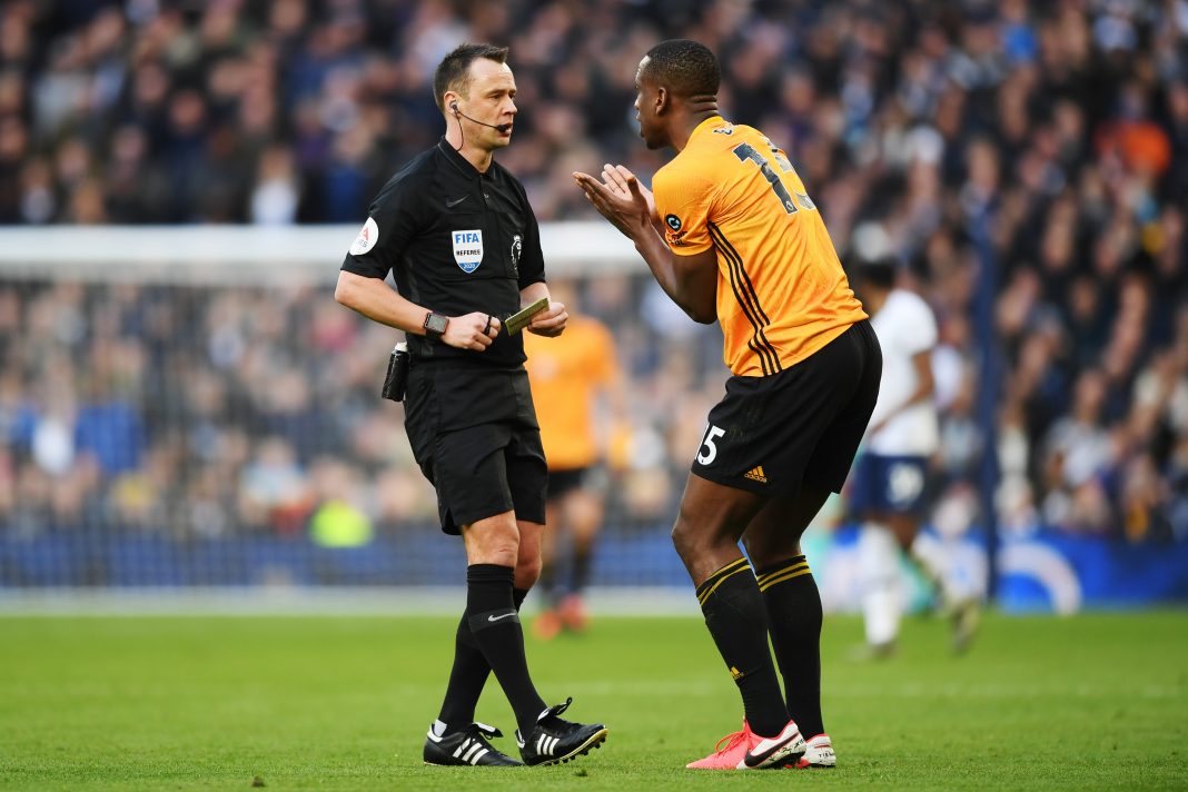 LONDON, ENGLAND - MARCH 01: Referee Stuart Attwell shows Willy Boly of Wolverhampton Wanderers a yellow card during the Premier League match between Tottenham Hotspur and Wolverhampton Wanderers at Tottenham Hotspur Stadium on March 01, 2020 in London, United Kingdom. (Photo by Shaun Botterill/Getty Images)