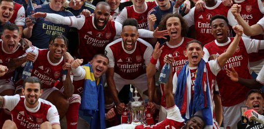 Arsenal's Gabonese striker Pierre-Emerick Aubameyang holds the winner's trophy as the team celebrates victory after the English FA Cup final football match between Arsenal and Chelsea at Wembley Stadium in London, on August 1, 2020. - Arsenal won the match 2-1. (Photo by Catherine Ivill / POOL / AFP)