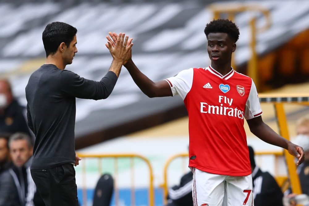 Arsenal's Spanish head coach Mikel Arteta (L) high-fives Arsenal's English striker Bukayo Saka (R) as Saka goes off substituted during the English Premier League football match between Wolverhampton Wanderers and Arsenal at the Molineux stadium in Wolverhampton, central England on July 4, 2020. (Photo by Michael Steele / POOL / AFP)