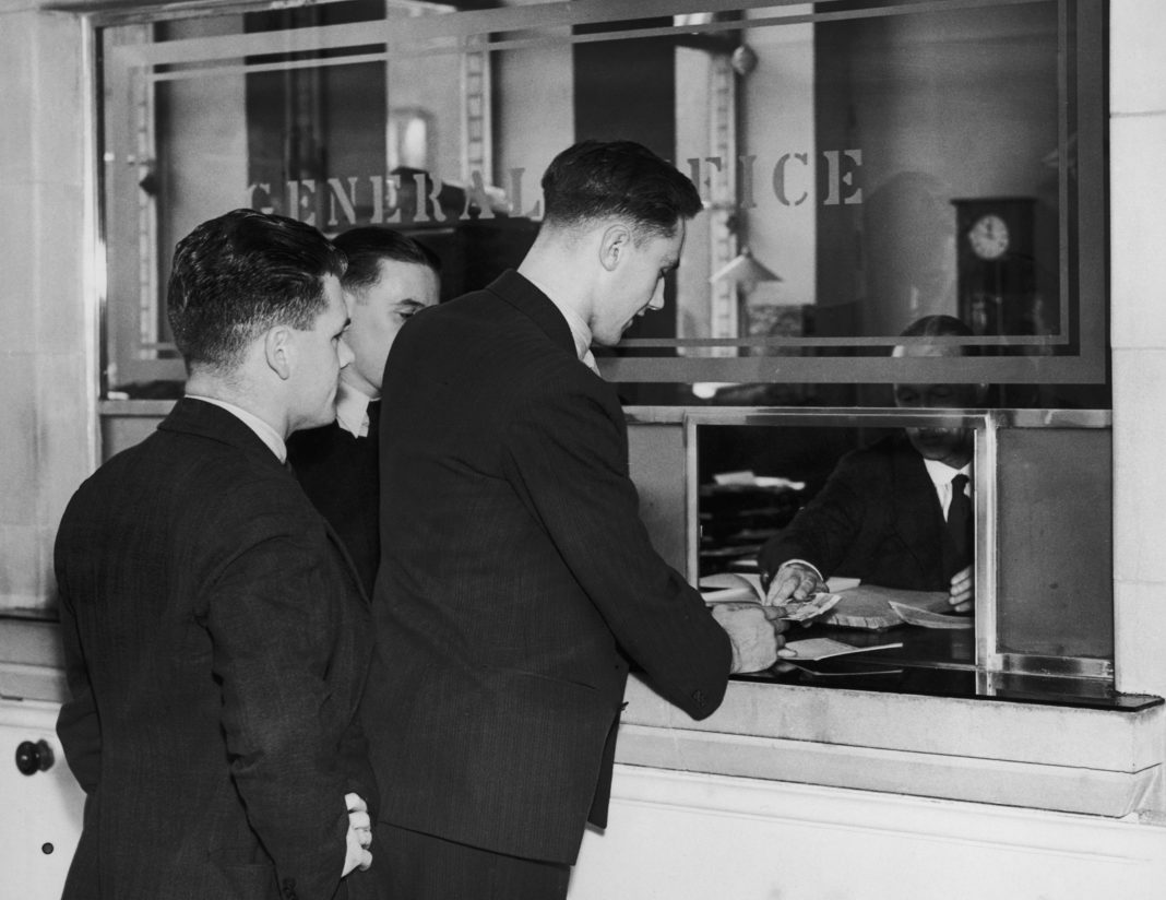 Arsenal wage bill - Arsenal footballers paying money into the bank at Highbury Stadium, North London as part of the club's saving scheme for players, 1st October 1938. (Photo by William G. Vanderson/Fox Photos/Getty Images)