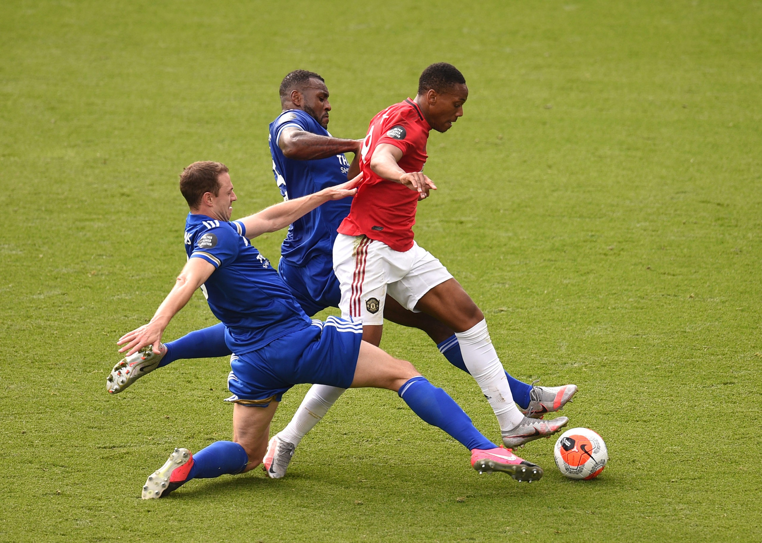 LEICESTER, ENGLAND - JULY 26: Anthony Martial of Manchester United is tackled by Wes Morgan and Jonny Evans both of Leicester City leading to a penalty during the Premier League match between Leicester City and Manchester United at The King Power Stadium on July 26, 2020 in Leicester, England.Football Stadiums around Europe remain empty due to the Coronavirus Pandemic as Government social distancing laws prohibit fans inside venues resulting in all fixtures being played behind closed doors. (Photo by Oli Scarff/Pool via Getty Images)