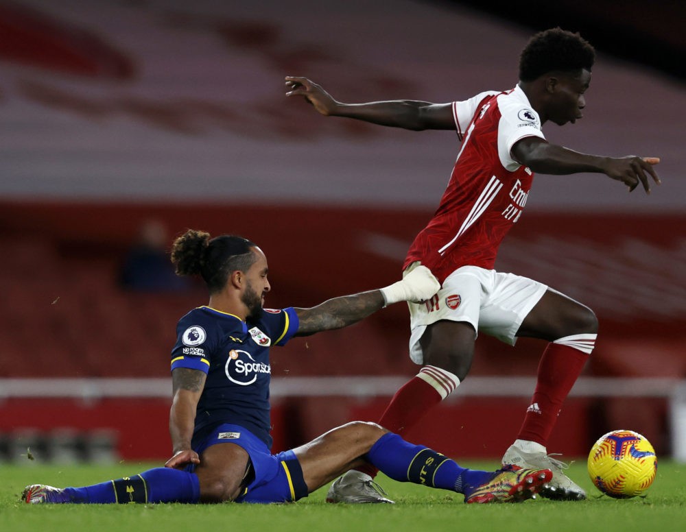 LONDON, ENGLAND - DECEMBER 16: Theo Walcott of Southampton tackles Bukayo Saka of Arsenal during the Premier League match between Arsenal and Southampton at Emirates Stadium on December 16, 2020 in London, England. The match will be played without fans, behind closed doors as a Covid-19 precaution. (Photo by Adrian Dennis - Pool/Getty Images)