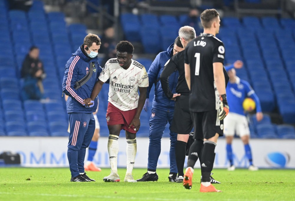BRIGHTON, ENGLAND - DECEMBER 29: Bukayo Saka of Arsenal receives medical treatment during the Premier League match between Brighton & Hove Albion and Arsenal at American Express Community Stadium on December 29, 2020 in Brighton, England. The match will be played without fans, behind closed doors as a Covid-19 precaution. (Photo by Neil Hall - Pool/Getty Images)