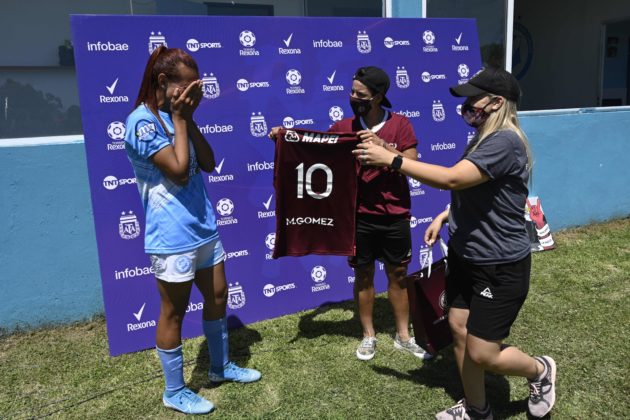 Argentine transgender footballer Mara Gomez (L) of Villa San Carlos reacts as she is given a jersey of Lanus with her name on it as present after an Argentina first division female football match against Between Villa San Carlos and Lanus at Genacio Salice stadium in Berisso, Buenos Aires, Argentina on December 7, 2020. - Gomez is the first transgender footballer to play in the first division of the Argentine female league. (Photo by JUAN MABROMATA / AFP)