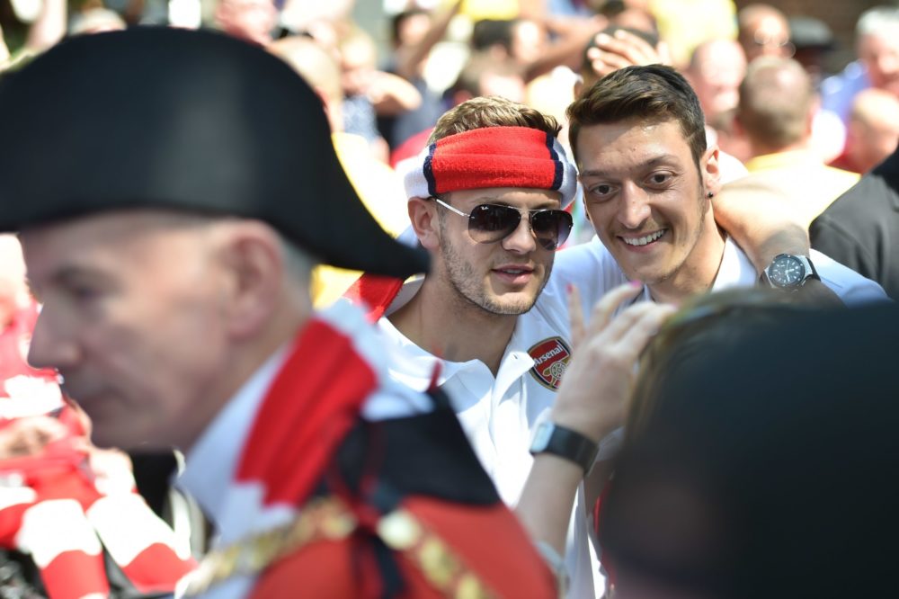 Arsenal's English midfielder Jack Wilshere (C) and Arsenal's German midfielder Mesut Ozil pose for photographs during their victory parade in London on May 18, 2014, following their win in the English FA Cup final football match on May 17, 2014 against Hull City.  Aaron Ramsey insists Arsenal's dramatic FA Cup final victory will be the springboard for more glory now the Gunners have finally ended their trophy drought. Ramsey scored the extra-time goal that clinched a 3-2 win over Hull in Saturday's clash at Wembley, putting silverware back in the Arsenal trophy cabinet for the first time since 2005.  AFP PHOTO /  LEON NEAL        