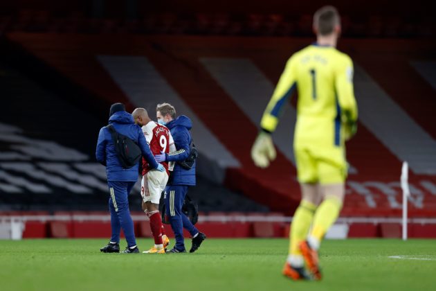 Arsenal's French striker Alexandre Lacazette (2L) is helped as he leaves the pitch injured during the English Premier League football match between Arsenal and Manchester United at the Emirates Stadium in London on January 30, 2021. (Photo by Ian KINGTON / IKIMAGES / AFP) / RESTRICTED TO EDITORIAL USE. No use with unauthorized audio, video, data, fixture lists, club/league logos or 'live' services. Online in-match use limited to 45 images, no video emulation. No use in betting, games or single club/league/player publications. (Photo by IAN KINGTON/IKIMAGES/AFP via Getty Images)