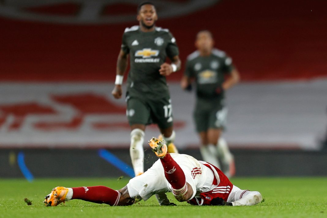 Arsenal's French striker Alexandre Lacazette crashes onto the pitch after clashing with Manchester United's English defender Harry Maguire during the English Premier League football match between Arsenal and Manchester United at the Emirates Stadium in London on January 30, 2021. (Photo by Ian KINGTON / IKIMAGES / AFP)