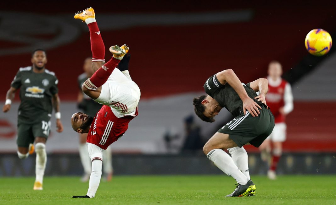 Arsenal's French striker Alexandre Lacazette (L) lands on his arm after clashing with Manchester United's English defender Harry Maguire during the English Premier League football match between Arsenal and Manchester United at the Emirates Stadium in London on January 30, 2021. (Photo by Ian KINGTON / IKIMAGES / AFP)