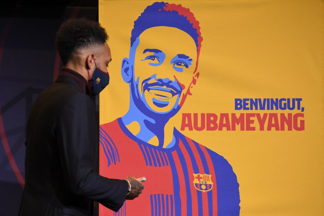 Barcelona's new player Gabonese forward Pierre-Emerick Aubameyang stands next to a poster reading 