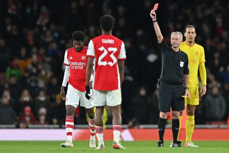 Referee Martin Atkinson (2nd R) shows a red card to Arsenal's Ghanaian midfielder Thomas Partey during the English League Cup semi-final second leg football match between Arsenal and Liverpool at the Emirates Stadium, in London on January 20, 2022. (Photo by JUSTIN TALLIS/AFP via Getty Images)