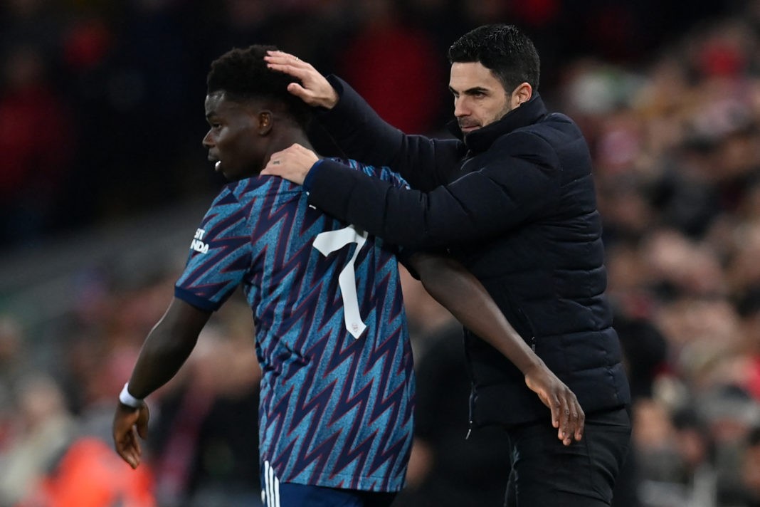 Arsenal's Spanish manager Mikel Arteta (R) speaks with Arsenal's English midfielder Bukayo Saka (L) during the English League Cup semi-final first leg football match between Liverpool and Arsenal at Anfield in Liverpool, north west England on January 13, 2022. (Photo by PAUL ELLIS/AFP via Getty Images)