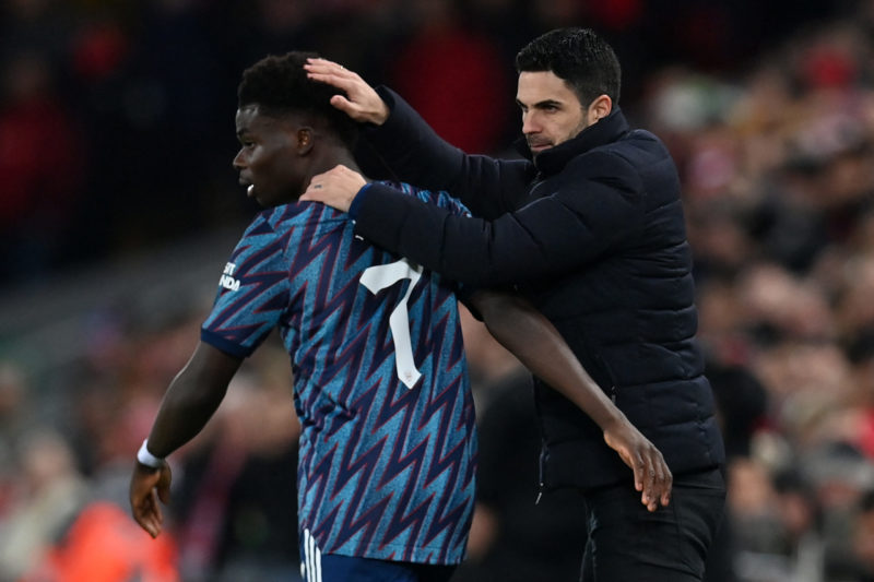 Arsenal's Spanish manager Mikel Arteta (R) speaks witj Arsenal's English midfielder Bukayo Saka (L) during the English League Cup semi-final first leg football match between Liverpool and Arsenal at Anfield in Liverpool, north west England on January 13, 2022. (Photo by PAUL ELLIS/AFP via Getty Images)
