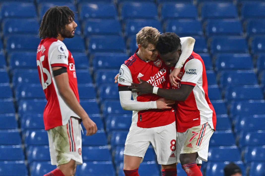 Arsenal's English midfielder Bukayo Saka (R) celebrates with Arsenal's Norwegian midfielder Martin Odegaard (C) after scoring their fourth goal from the penalty spot during the English Premier League football match between Chelsea and Arsenal at Stamford Bridge in London on April 20, 2022. - Arsenal won the game 4-2.(Photo by GLYN KIRK/AFP via Getty Images)