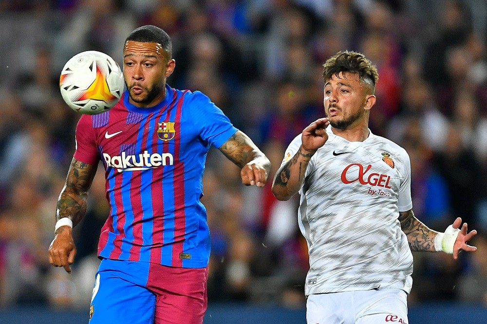 Barcelona's Dutch forward Memphis Depay (L) eyes the ball next to Real Mallorca's Spanish defender Pablo Maffeo prior to scoring the opener during the Spanish League football match between FC Barcelona and RCD Mallorca at the Camp Nou stadium in Barcelona on May 1, 2022. (Photo by PAU BARRENA/AFP via Getty Images)
