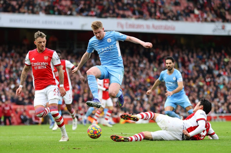 LONDON, ENGLAND - JANUARY 01: Kevin De Bruyne of Manchester City is tackled by  Takehiro Tomiyasu of Arsenal during the Premier League match between Arsenal and Manchester City at Emirates Stadium on January 01, 2022 in London, England. (Photo by Catherine Ivill/Getty Images)