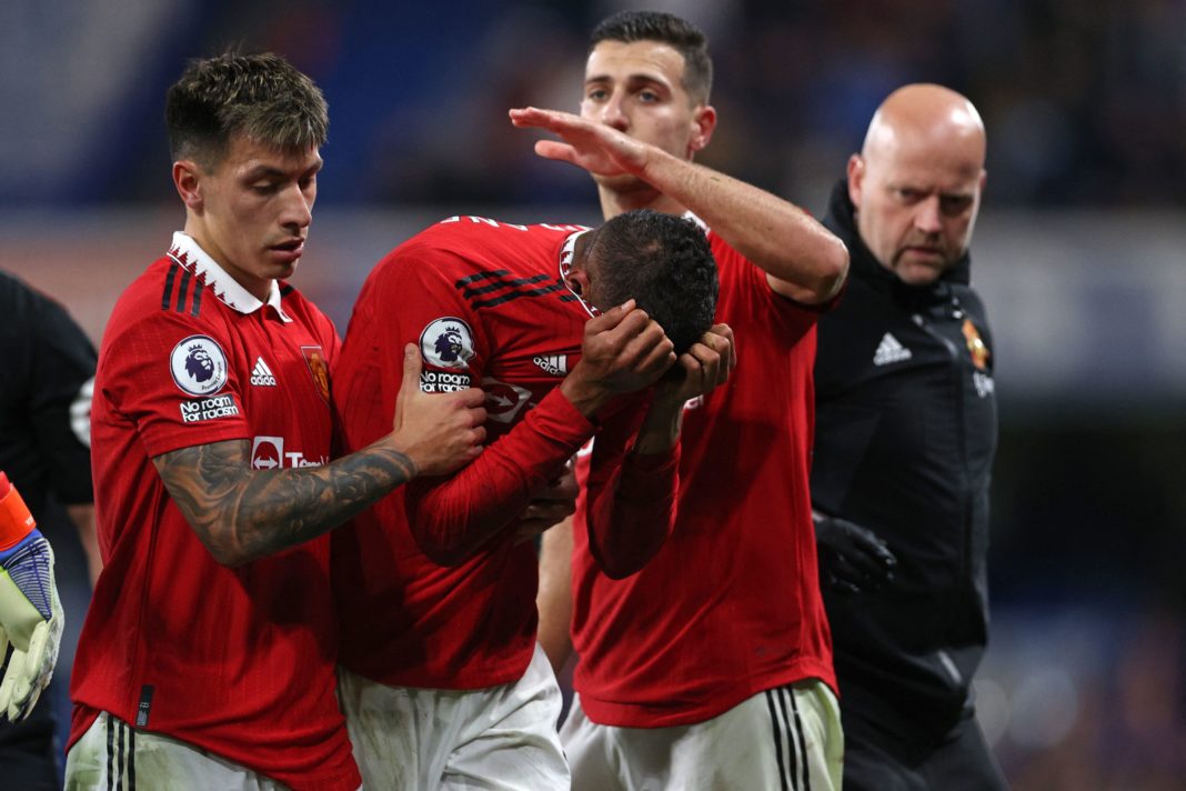 Manchester United's French defender Raphael Varane (C) is consoled by Manchester United's Argentinian defender Lisandro Martinez (L) and Manchester United's Portuguese defender Diogo Dalot (2nd R) as he leaves the pitch after picking up an injury during the English Premier League football match between Chelsea and Manchester United at Stamford Bridge in London on October 22, 2022.(Photo by ADRIAN DENNIS/AFP via Getty Images)