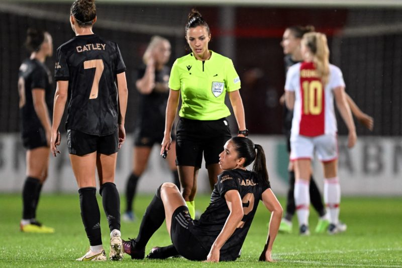 Arsenal's Australian defender Steph Catley (L) and Spanish referee Marta Huerta de Aza (C) look on as Arsenal's Brazilian midfielder Rafaelle Souza (bottom) sits on the pitch uring the UEFA Champions League women's second round football match between Ajax Amsterdam and Arsenal FC at De Toekomst sports complex in Amsterdam, on September 28, 2022.(Photo by GERRIT VAN KEULEN/ANP/AFP via Getty Images)