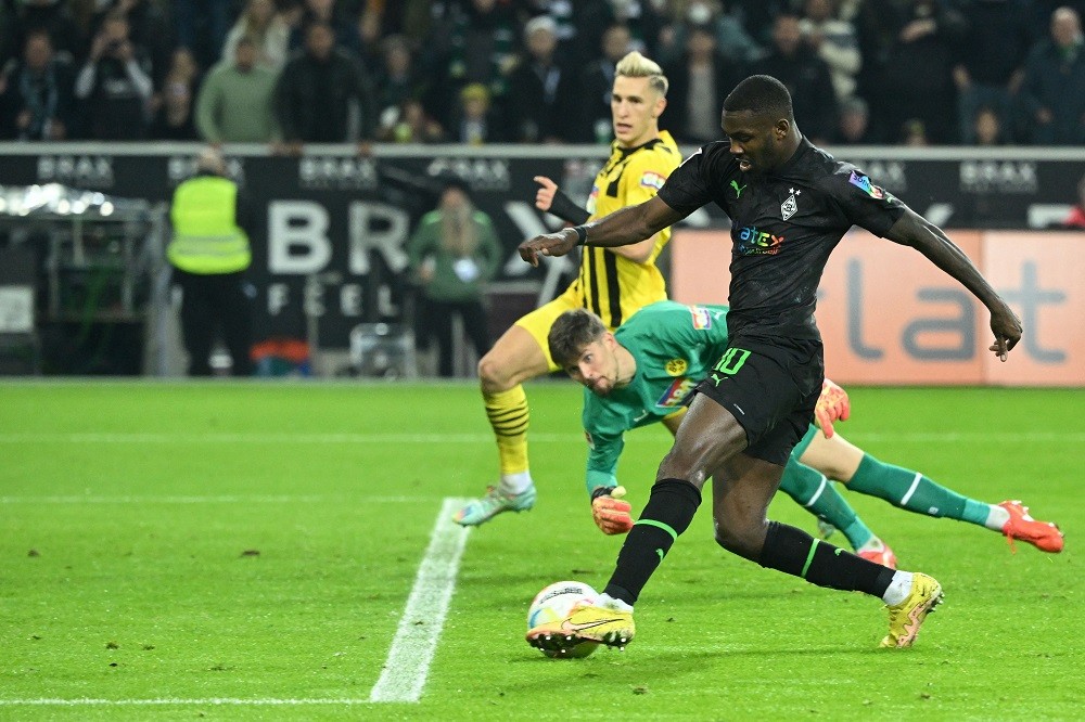 Moenchengladbach's French forward Marcus Thuram (R) shoots to scoring a goal during the German first division Bundesliga football match between Borussia Moenchengladbach v Borussia Dortmund in Moenchengladbach, western Germany, on November 11, 2022. (Photo by INA FASSBENDER/AFP via Getty Images)