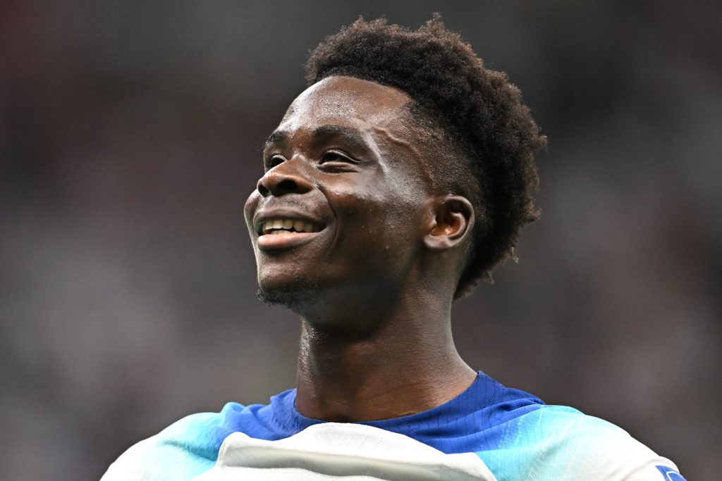 England's forward #17 Bukayo Saka celebrates scoring his team's third goal during the Qatar 2022 World Cup round of 16 football match between England and Senegal at the Al-Bayt Stadium in Al Khor, north of Doha on December 4, 2022.(Photo by PAUL ELLIS/AFP via Getty Images)