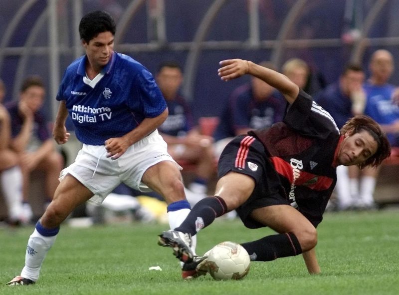 EAST RUTHERFORD, UNITED STATES:  Victor Zapata (R) of Argentina's River Plate keeps control of the ball as he falls next to Mikel Arteta of Scotland's Glasgow Rangers (L) in the first half 13 July, 2002 at Giants Stadium in East Rutherford, NJ.  (Photo credit MATT CAMPBELL/AFP via Getty Images)