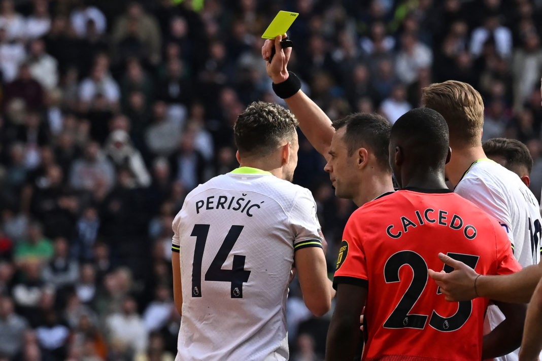 English referee Stuart Attwell (C) shows a yellow card to Tottenham Hotspur's Croatian midfielder Ivan Perisic (L) during the English Premier League football match between Tottenham Hotspur and Brighton and Hove Albion at Tottenham Hotspur Stadium in London, on April 8, 2023. (Photo by BEN STANSALL/AFP via Getty Images)
