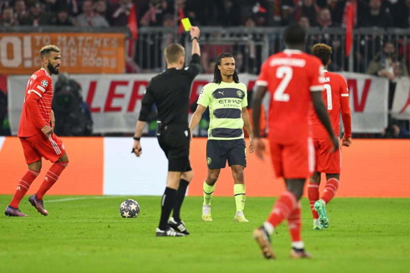 MUNICH, GERMANY - APRIL 19: Nathan Ake of Manchester City is shown a yellow card by Referee Clement Turpin during the UEFA Champions League quarterfinal second leg match between FC Bayern München and Manchester City at Allianz Arena on April 19, 2023 in Munich, Germany. (Photo by Matthias Hangst/Getty Images)