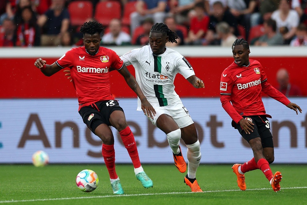 LEVERKUSEN, GERMANY: Edmond Tapsoba of Bayer 04 Leverkusen runs with the ball whilst under pressure from Kouadio Kone of Borussia Moenchengladbach during the Bundesliga match between Bayer 04 Leverkusen and Borussia Mönchengladbach at BayArena on May 21, 2023. (Photo by Lars Baron/Getty Images)