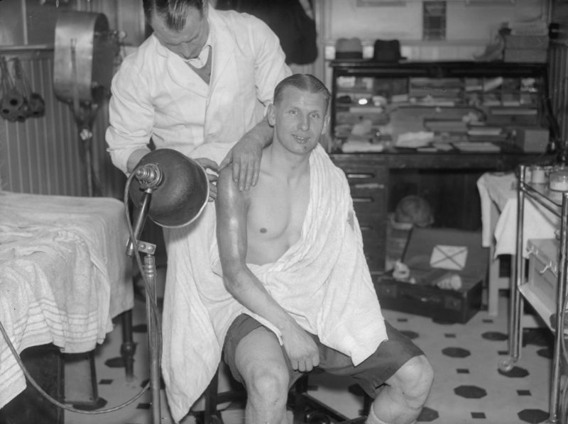 1st April 1935: Arsenal football player Cliff Bastin (1912 - 1991) receives treatment from his trainer Tom Whittaker at Highbury after receiving an injury in the match against Aston Villa. (Photo by Fred Morley/Fox Photos/Getty Images)