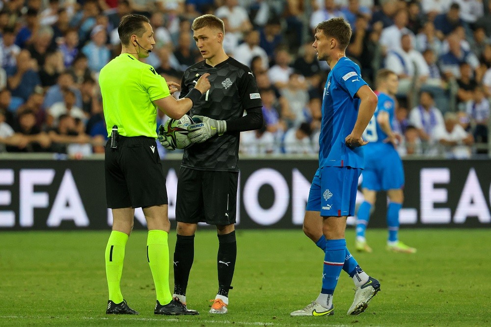 Latvian referee Andris Treimanis (L) speaks with Iceland's goalkeeper Runar Alex Runarsson (C) during the UEFA Nations League - League B Group 2 - football match between Israel and Iceland at the Samy Ofer stadium in the Israeli city of Haifa on June 2, 2022. (Photo by JACK GUEZ/AFP via Getty Images)