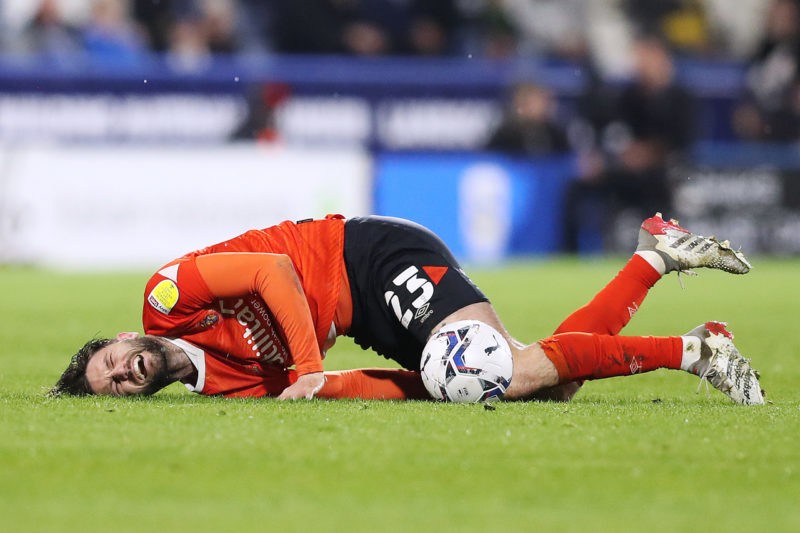 HUDDERSFIELD, ENGLAND - APRIL 11: Henri Lansbury of Luton Town lays injured during the Sky Bet Championship match between Huddersfield Town and Luton Town at John Smith's Stadium on April 11, 2022 in Huddersfield, England. (Photo by Charlotte Tattersall/Getty Images)