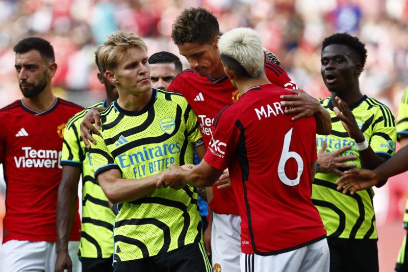 EAST RUTHERFORD, NEW JERSEY - JULY 22: Martin Odegaard #8 of Arsenal shakes hands with Lisandro Martinez #6 and Raphael Varane #19 of Manchester United during a pre-season friendly match at MetLife Stadium on July 22, 2023 in East Rutherford, New Jersey. (Photo by Rich Schultz/Getty Images)