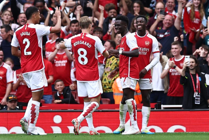 Arsenal's English midfielder #07 Bukayo Saka (2R) celebrates with teammates after his deflected shot makes it 1-0 during the English Premier League football match between Arsenal and Tottenham Hotspur at the Emirates Stadium in London on September 24, 2023. (Photo by HENRY NICHOLLS/AFP via Getty Images)