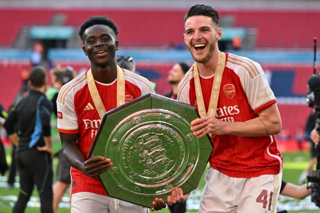 Arsenal's English midfielder Bukayo Saka (L) and Arsenal's English midfielder Declan Rice (R) pose with the trophy as Arsenal players celebrate winning the English FA Community Shield football match between Arsenal and Manchester City at Wembley Stadium, in London, August 6, 2023. Arsenal won after a 4-1 penalty shoot-out win, following the 1-1 draw in 90 minutes. (Photo by GLYN KIRK/AFP via Getty Images)