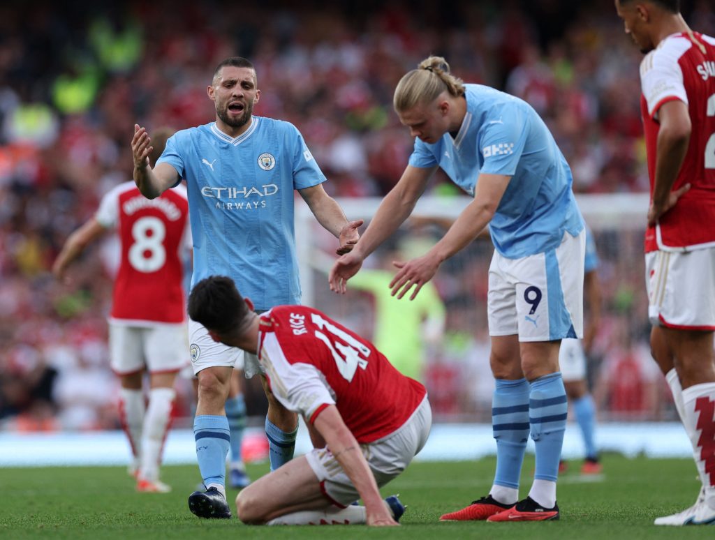 Manchester City's Croatian midfielder #08 Mateo Kovacic (L) and Manchester City's Norwegian striker #09 Erling Haaland (R) gestures to Arsenal's English midfielder #41 Declan Rice (C) after he goes down under a challenge from Kovacic during the English Premier League football match between Arsenal and Manchester City at the Emirates Stadium in London on October 8, 2023. (Photo by ADRIAN DENNIS/AFP via Getty Images)