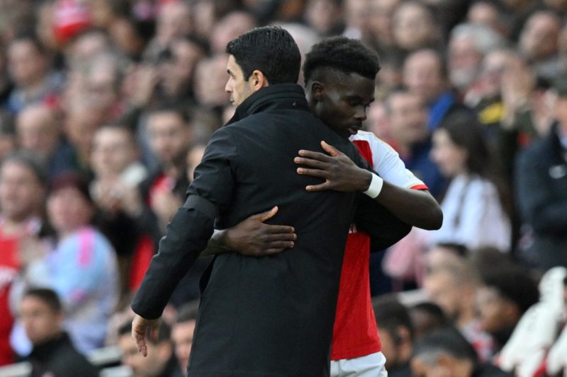 Arsenal's Spanish manager Mikel Arteta (L) embraces Arsenal's English midfielder #07 Bukayo Saka (R) he leaves the game after being substituted during the English Premier League football match between Arsenal and Sheffield United at the Emirates Stadium in London on October 28, 2023. (Photo by GLYN KIRK/AFP via Getty Images)