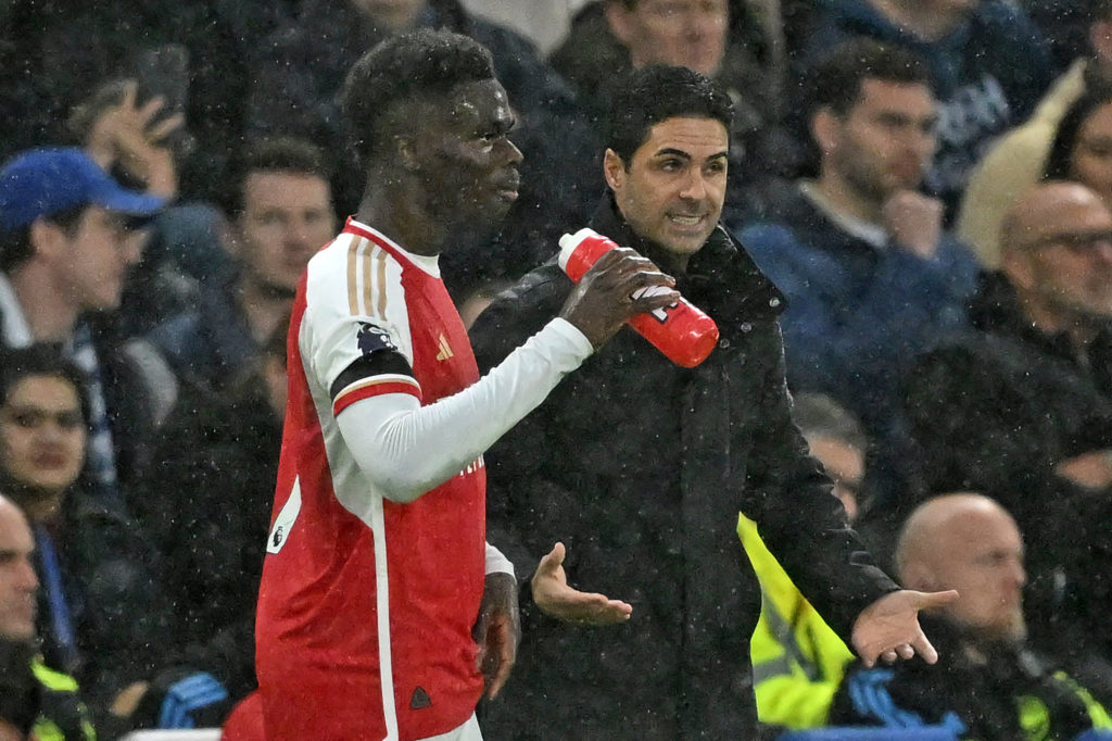 Arsenal's Spanish manager Mikel Arteta (R) speaks with Arsenal's English midfielder #07 Bukayo Saka (L) during the English Premier League football match between Chelsea and Arsenal at Stamford Bridge in London on October 21, 2023. (Photo by JUSTIN TALLIS/AFP via Getty Images)