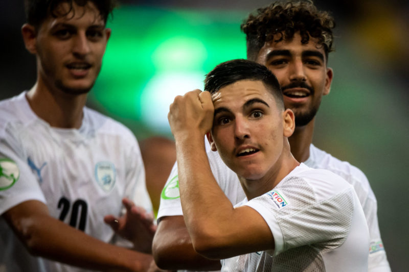 Israel's midfielder Oscar Gloukh celebrates scoring the opening goal with his teammates during the UEFA Under-19 European Championship semi-final football match between France and Israel at the DAC Arena in Dunajska Streda, Slovakia on June 28, 2022. (Photo by VLADIMIR SIMICEK/AFP via Getty Images)