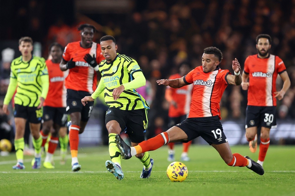 LUTON, ENGLAND: Gabriel Magalhaes of Arsenal passes the ball whilst under pressure from Jacob Brown of Luton Town during the Premier League match between Luton Town and Arsenal FC at Kenilworth Road on December 05, 2023. (Photo by Julian Finney/Getty Images)
