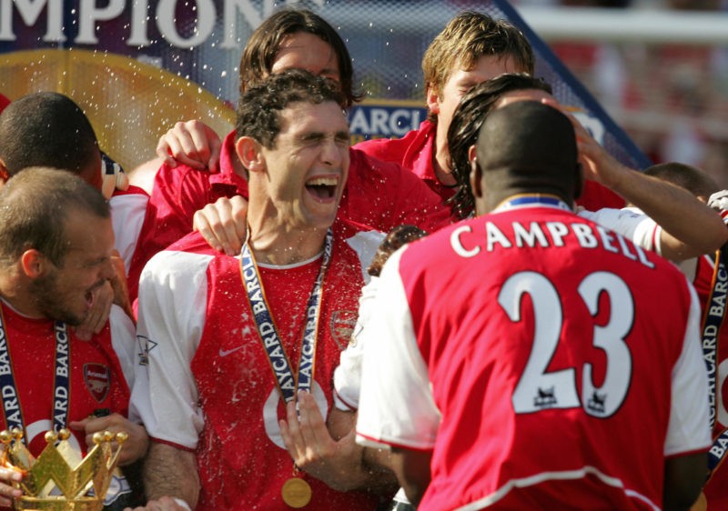 LONDON, UNITED KINGDOM:  Arsenal's Sol Campbell (R) sprays Martin Keown with Champaigne after Arsenal won the Premiership title and defeating Leicsester City 15 May, 2004 at Highbury in London. Arsenal defeated Leicester City 2-1 and finish the season undefeated. (Photo credit JIM WATSON/AFP via Getty Images)