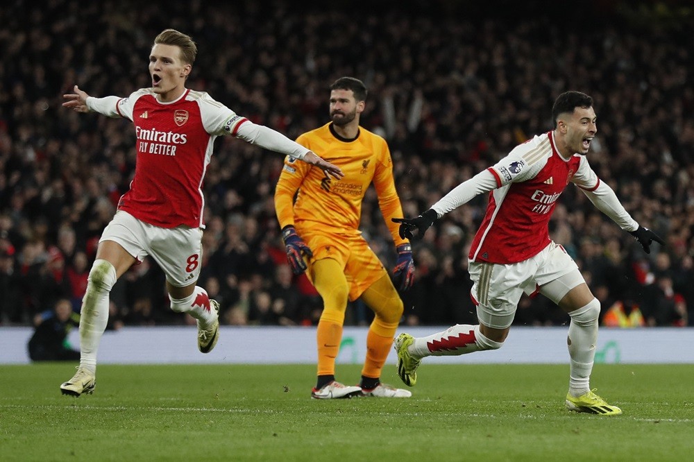 Arsenal's Gabriel Martinelli (R) celebrates with Martin Odegaard (L) next to Liverpool's Alisson Becker (C) after scoring his team second goal during the English Premier League football match between Arsenal and Liverpool at the Emirates Stadium in London on February 4, 2024. (Photo by IAN KINGTON/IKIMAGES/AFP via Getty Images)